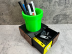 a green cup filled with pens and pencils