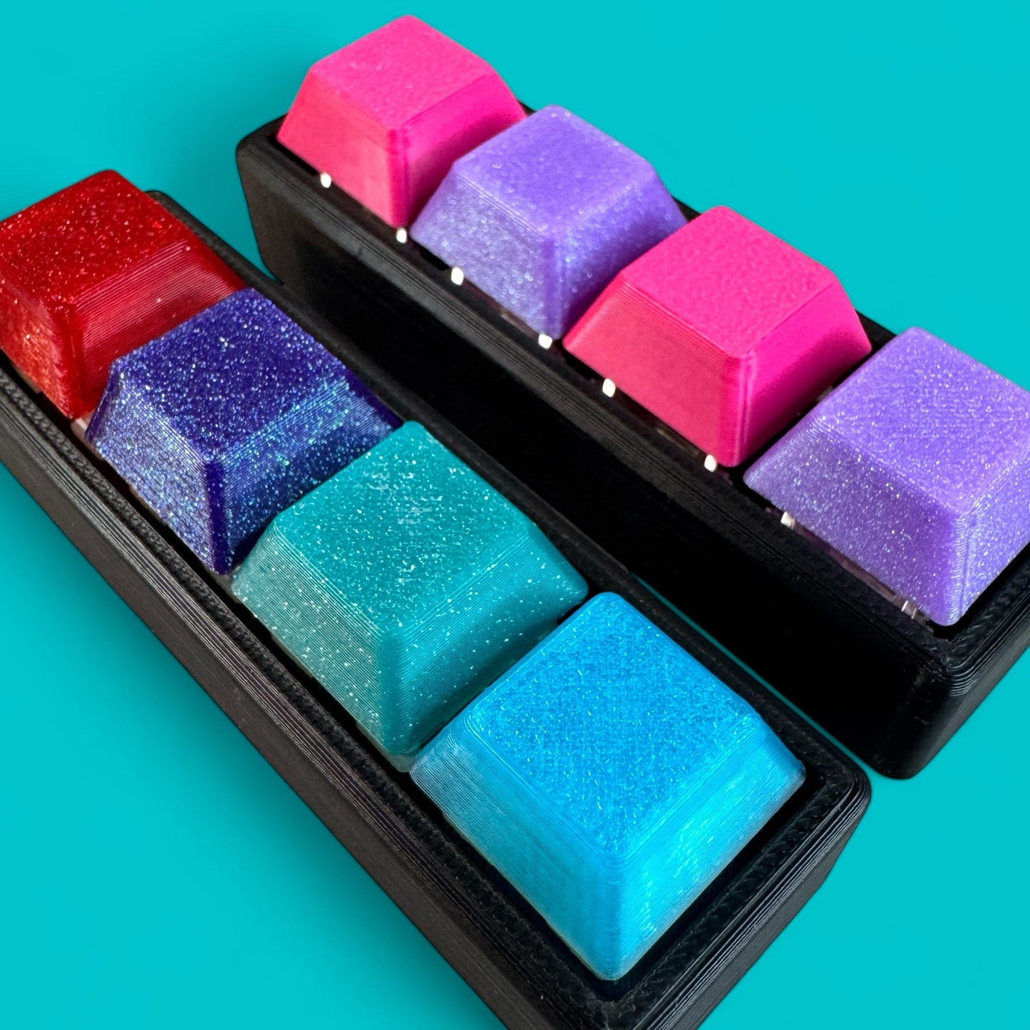 Colorful keycaps on a black keyboard tray against a teal background