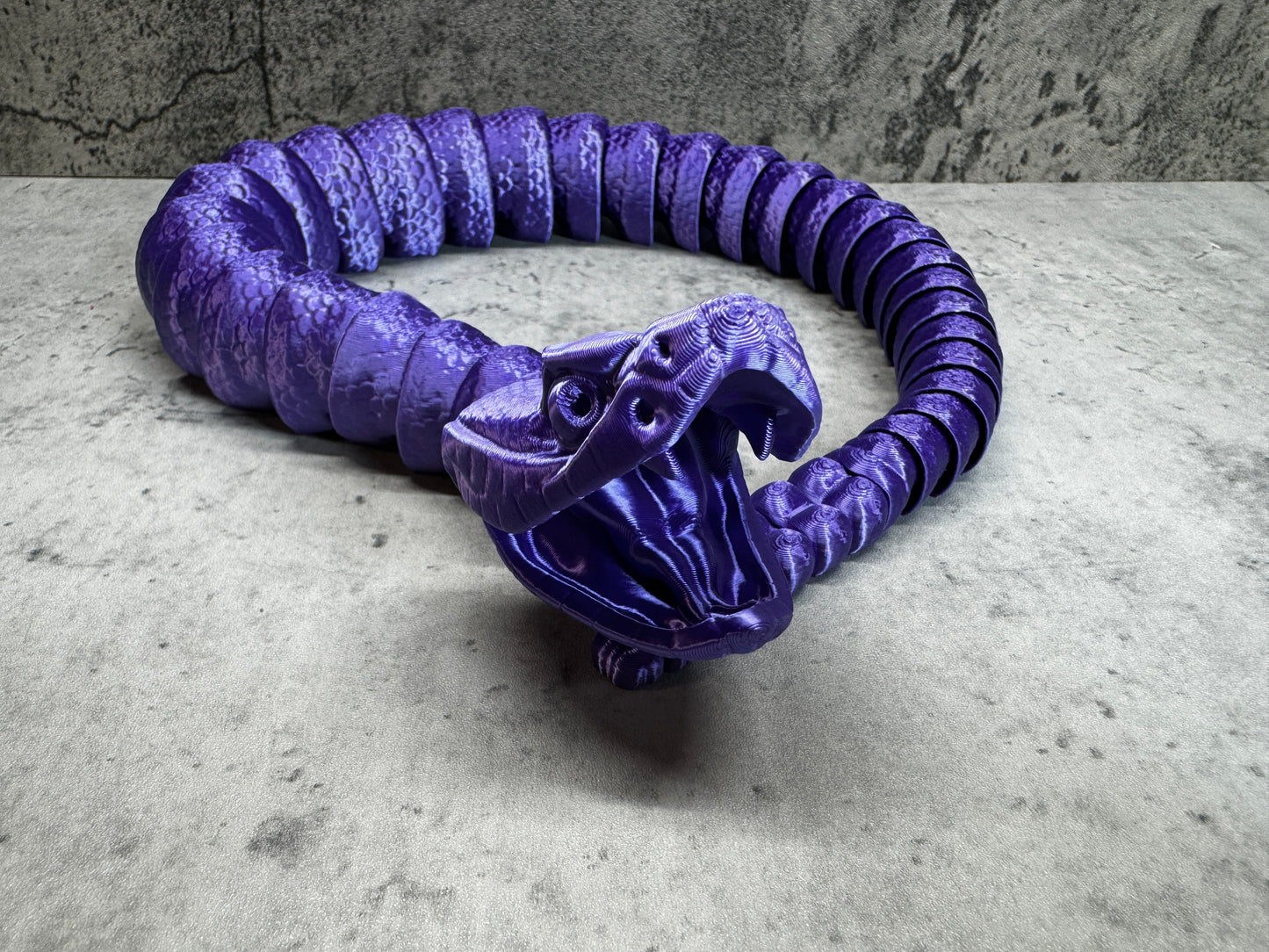 
                  
                    a purple snake sculpture sitting on top of a table
                  
                