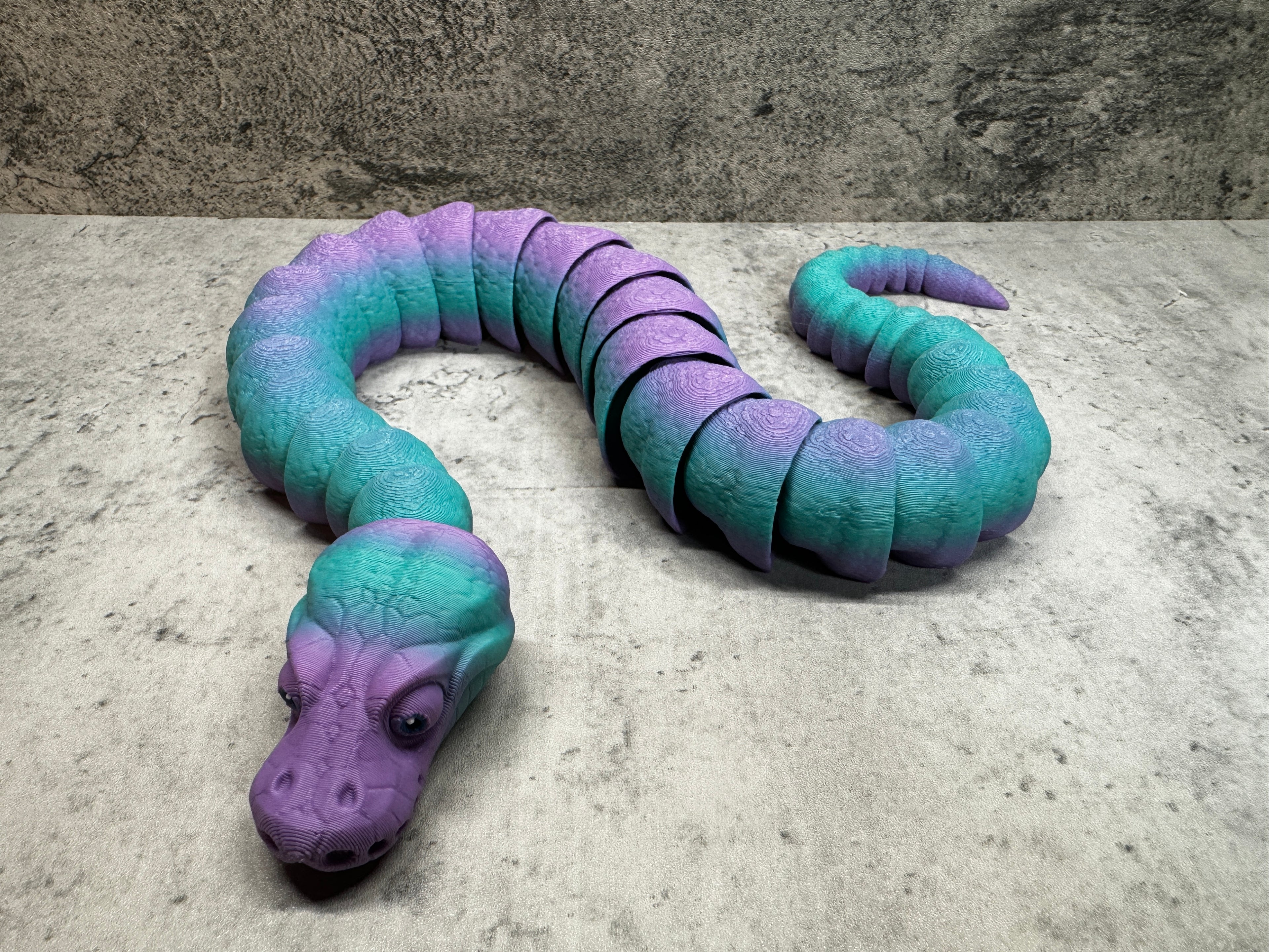 a purple and blue snake laying on the ground