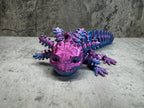 a purple and blue toy lizard sitting on top of a table