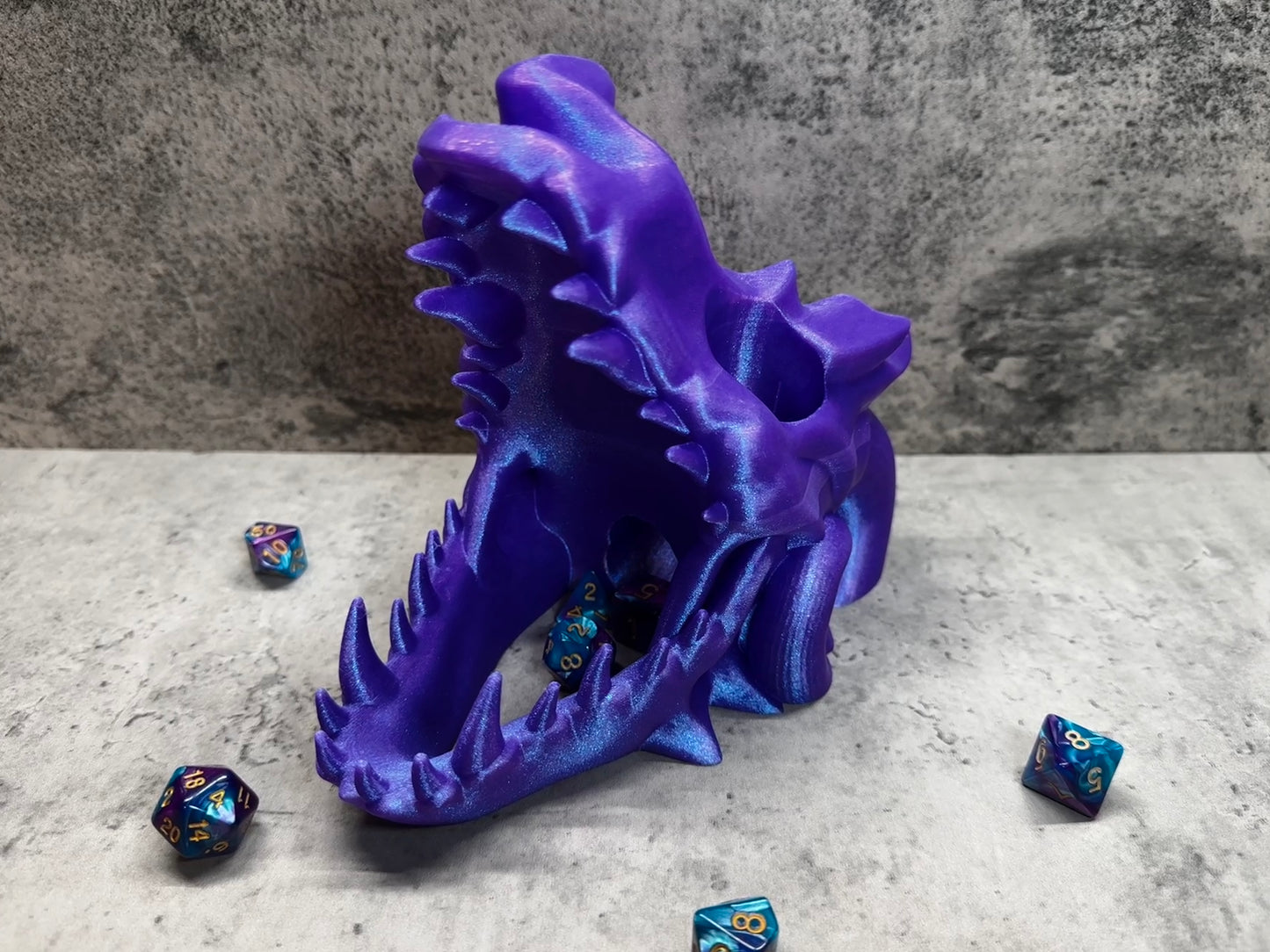 
                  
                    a close up of a purple dragon head with dice scattered around it
                  
                