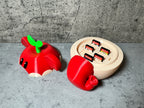 a red toy with a green leaf on top of it