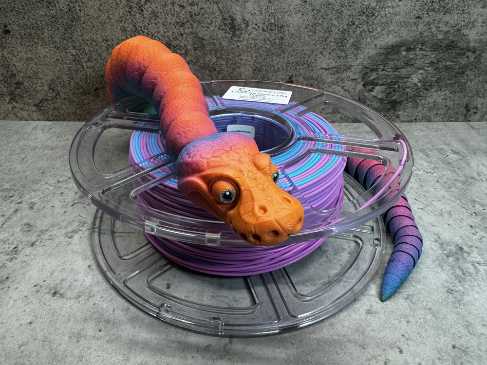 
                  
                    a purple and orange toy snake sitting on top of a spool of purple wire
                  
                