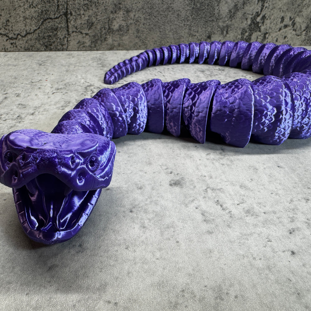 
                  
                    a purple snake sculpture sitting on top of a table
                  
                