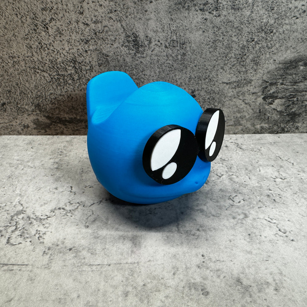 
                  
                    a blue toy with black eyes and a black nose
                  
                