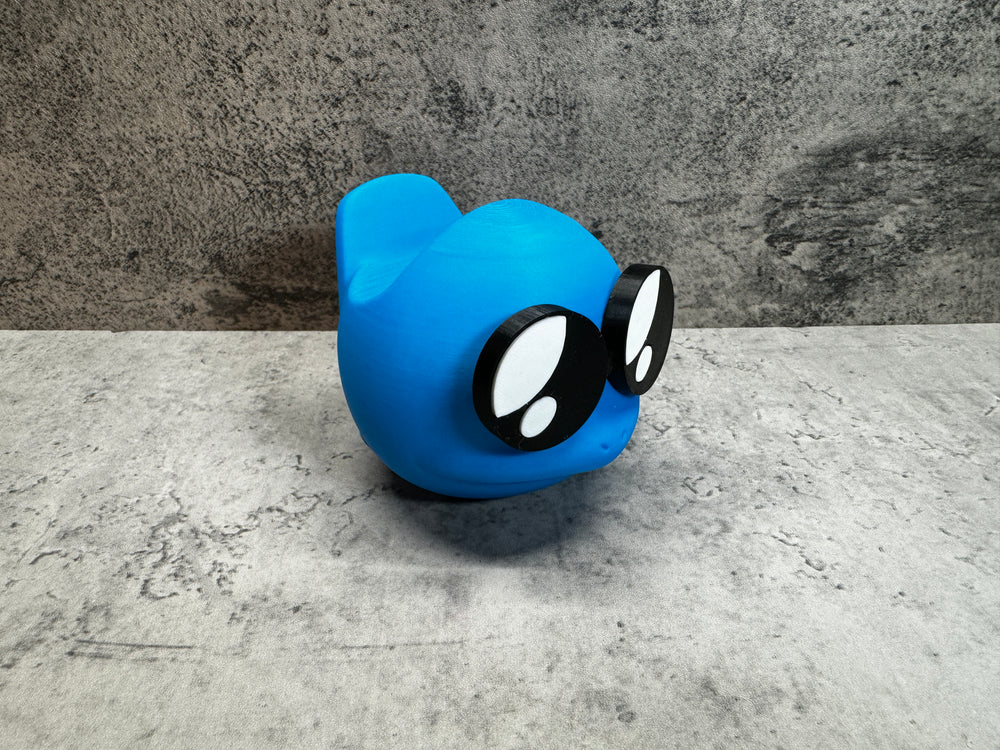 
                  
                    a blue toy with black eyes and a black nose
                  
                