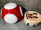 a red and white mushroom shaped object next to a nintendo game controller