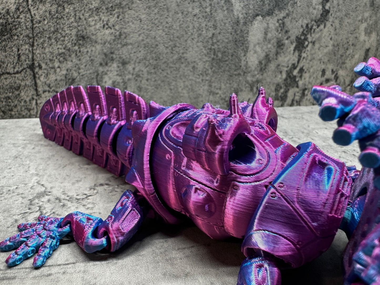 
                  
                    a purple lizard statue sitting on top of a cement floor
                  
                