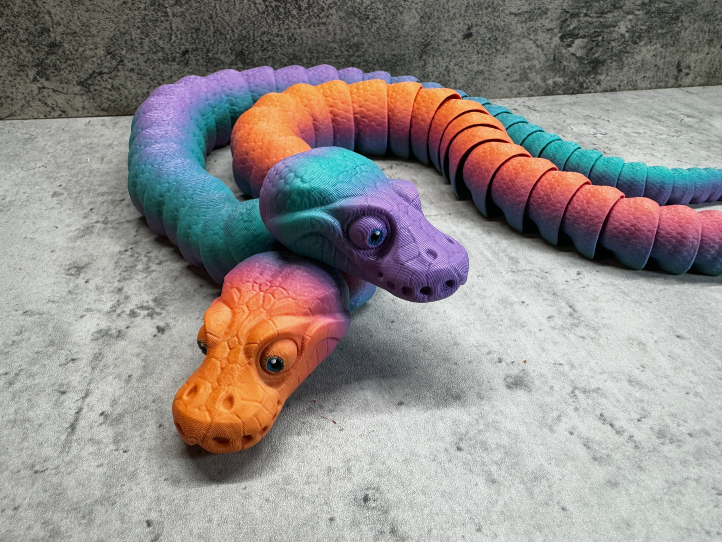a toy snake laying on the ground next to a toy snake