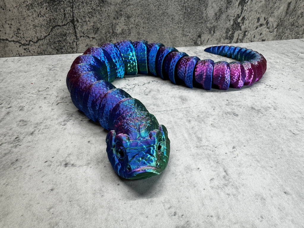 a blue and purple snake laying on top of a cement floor