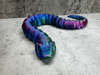 a blue and purple snake laying on top of a cement floor