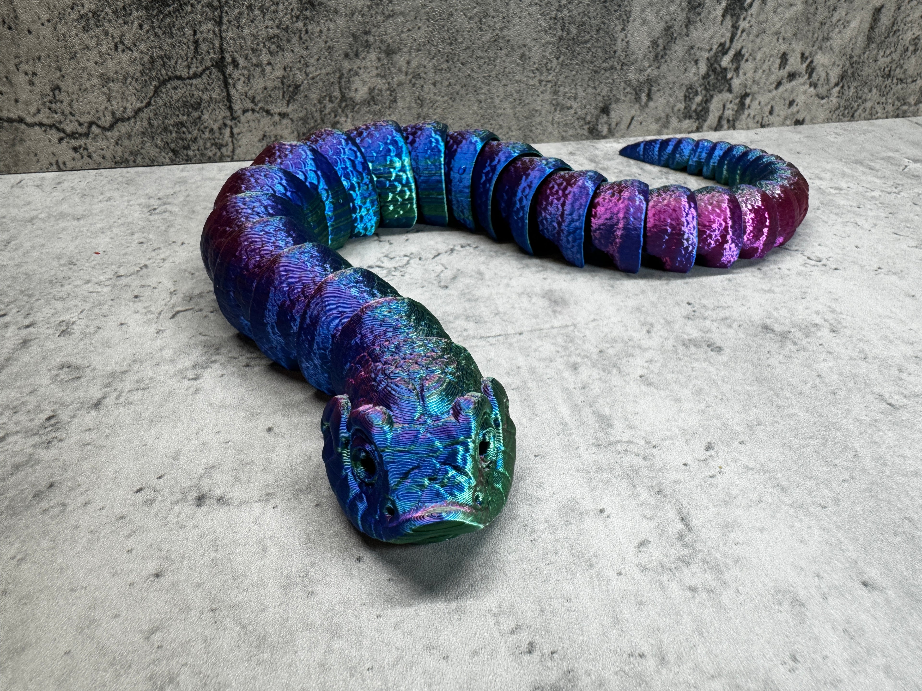 a blue and purple snake laying on top of a cement floor