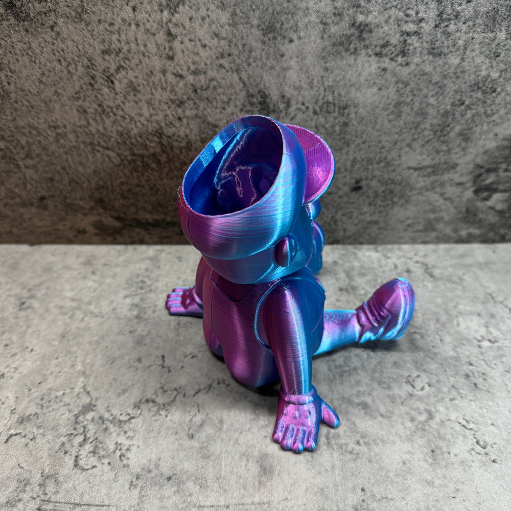 
                  
                    a purple and blue toy sitting on top of a cement floor
                  
                