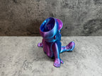 a purple and blue toy sitting on top of a cement floor