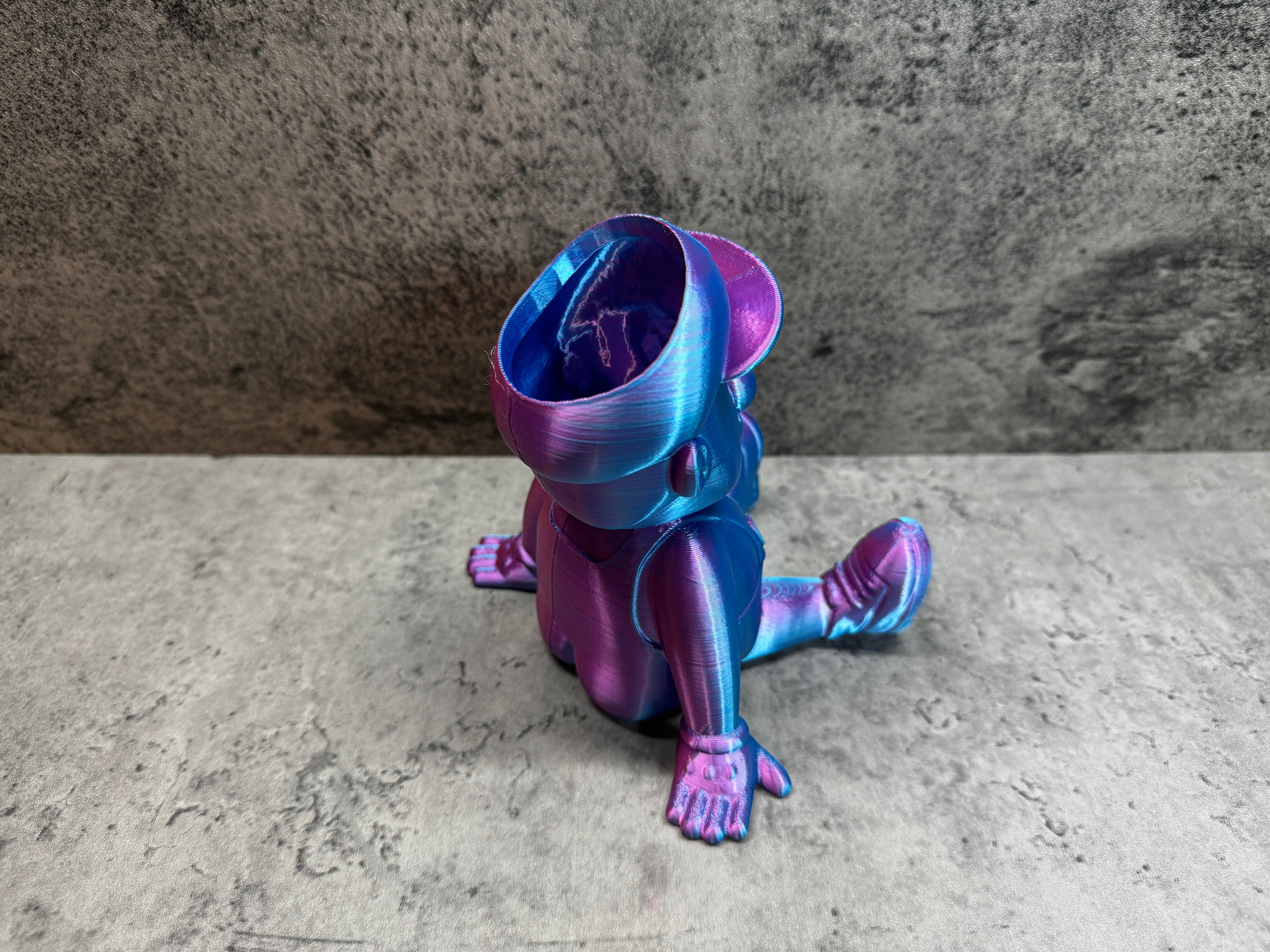 a purple and blue toy sitting on top of a cement floor