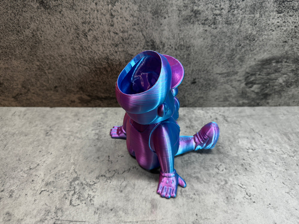 
                  
                    a purple and blue toy sitting on top of a cement floor
                  
                
