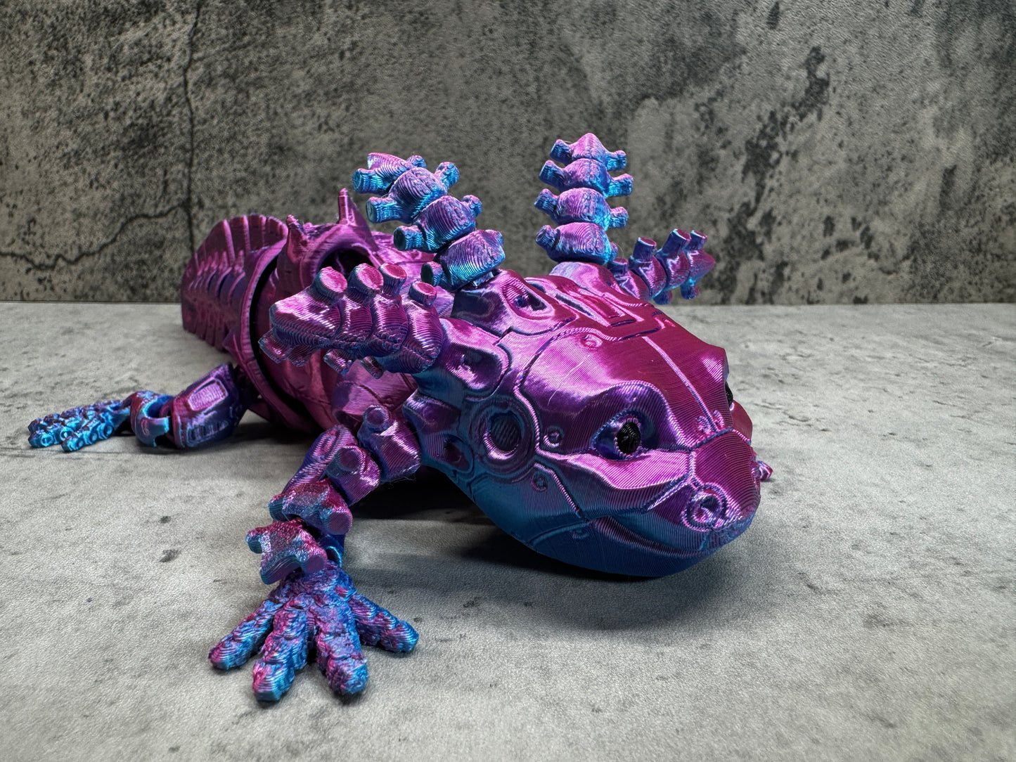 a purple and blue toy lizard laying on the ground