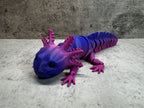 a purple and blue toy lizard laying on the ground
