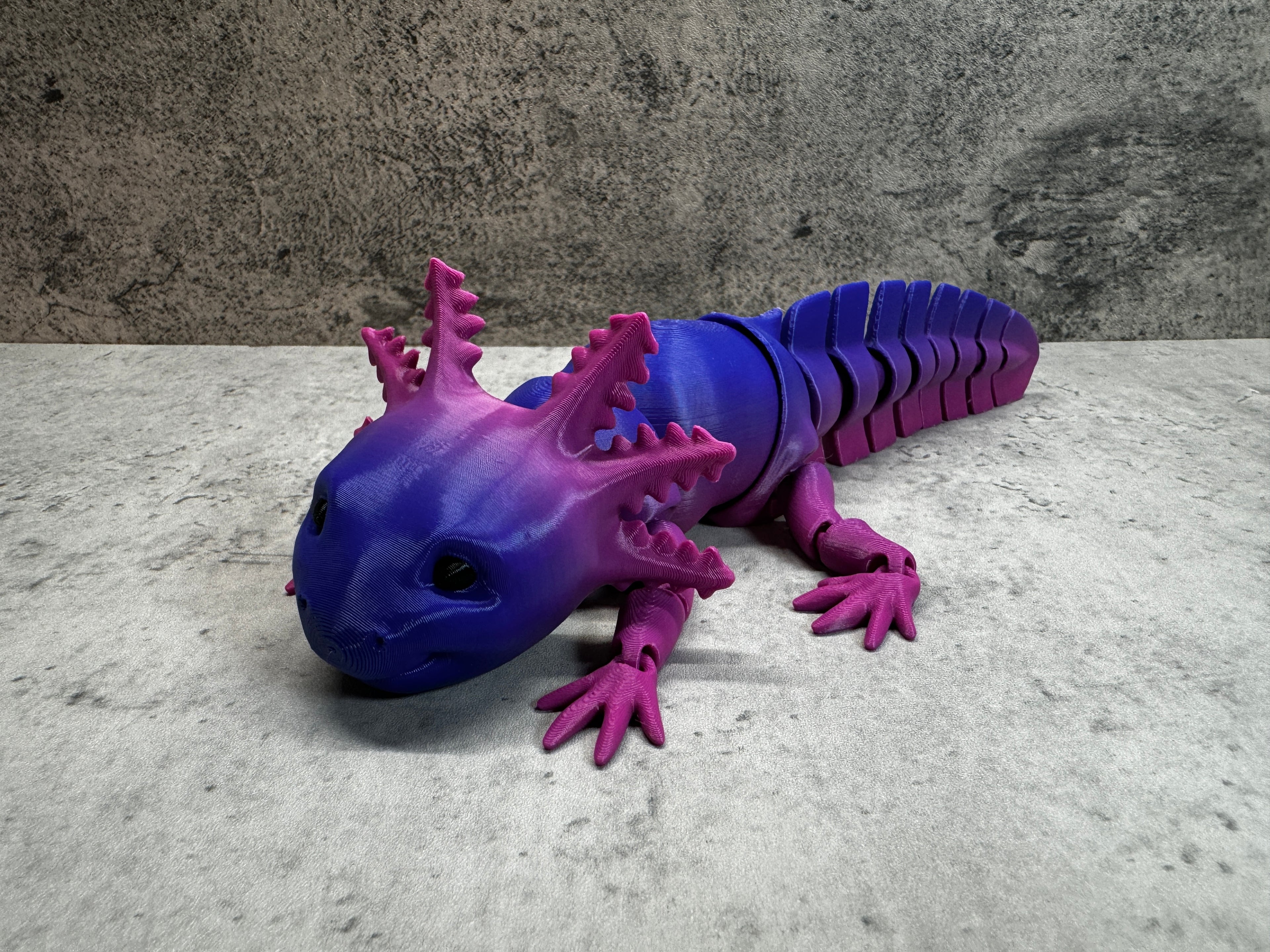 a purple and blue toy lizard laying on the ground