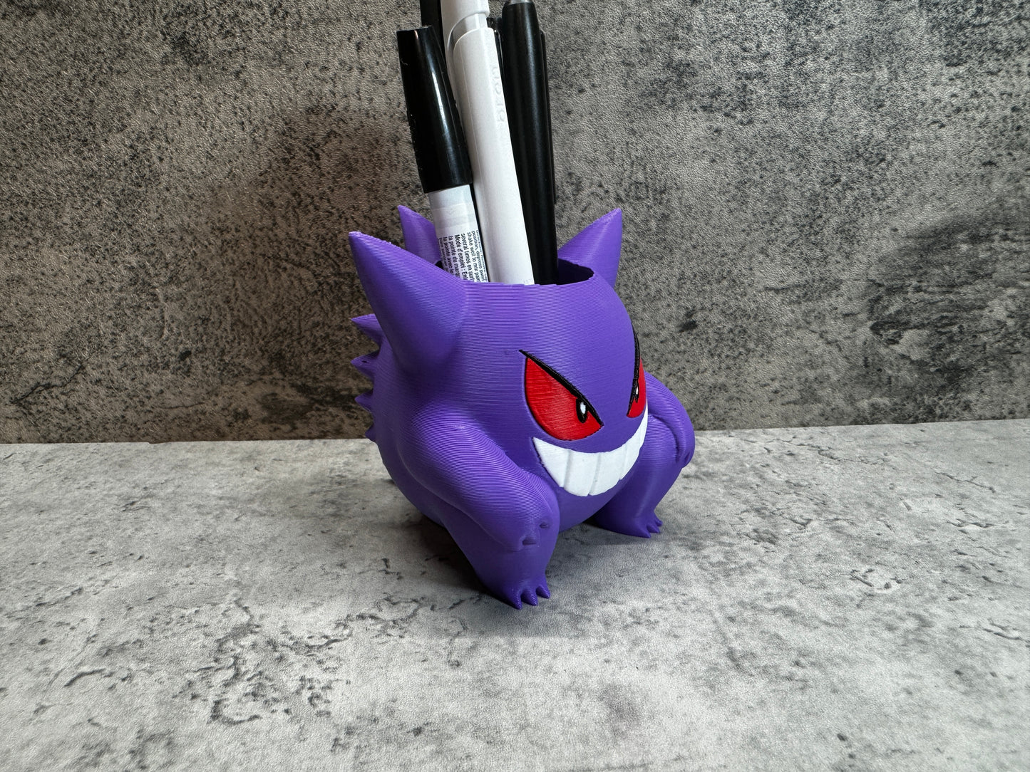 
                  
                    a purple toy with red eyes and a toothbrush holder
                  
                