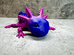 a purple and blue toy lizard sitting on a table