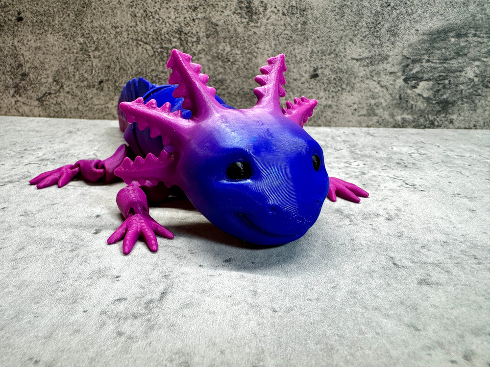 
                  
                    a purple and blue toy lizard sitting on a table
                  
                