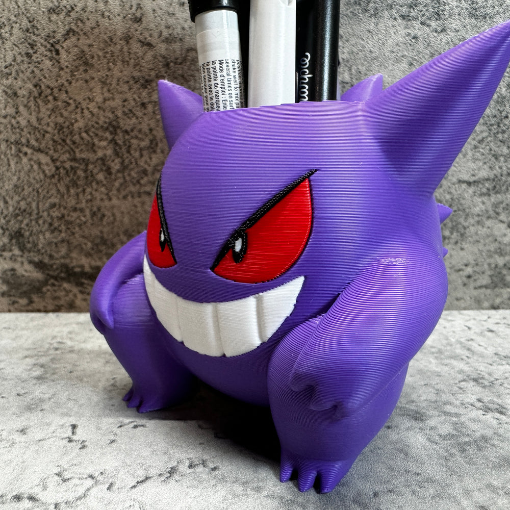 
                  
                    a purple toy with red eyes and a toothbrush holder
                  
                