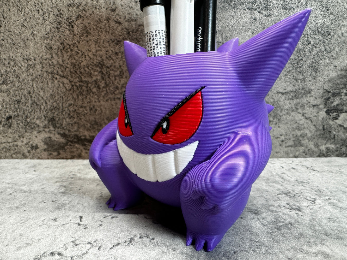 
                  
                    a purple toy with red eyes and a toothbrush holder
                  
                