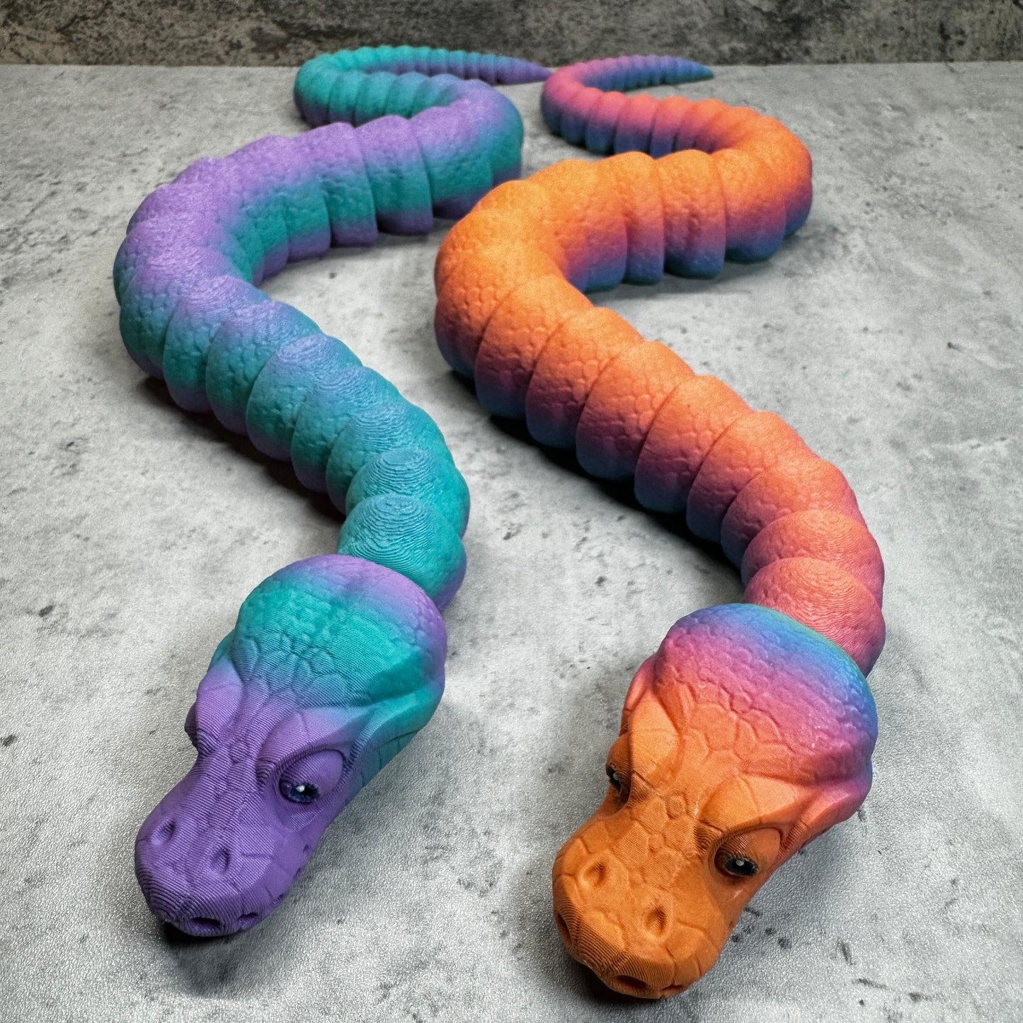 
                  
                    a toy snake and a fake snake on the ground
                  
                