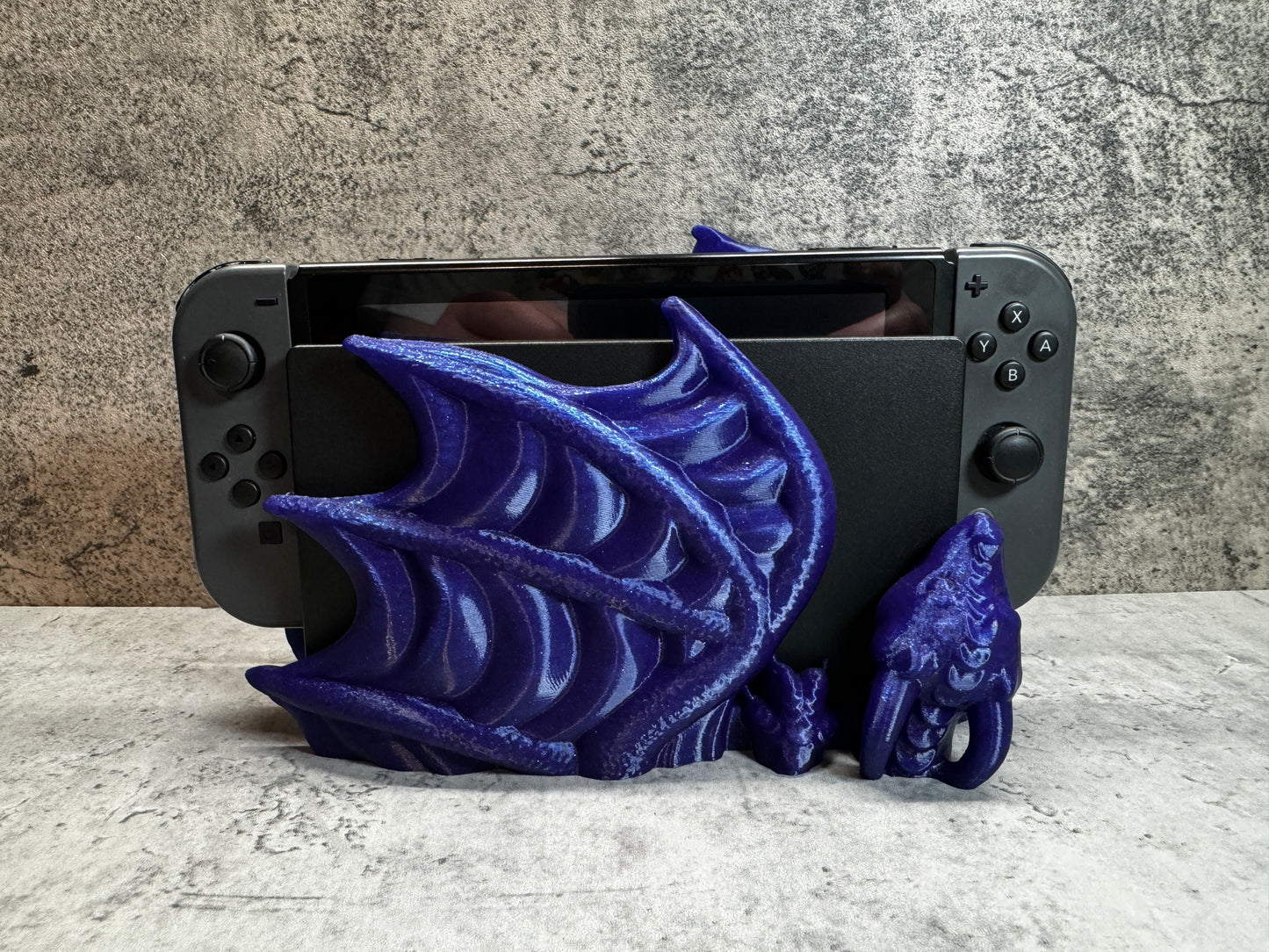 
                  
                    a purple dragon figurine sitting on top of a nintendo wii game console
                  
                