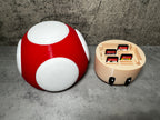 a red and white mushroom shaped object next to a nintendo game console