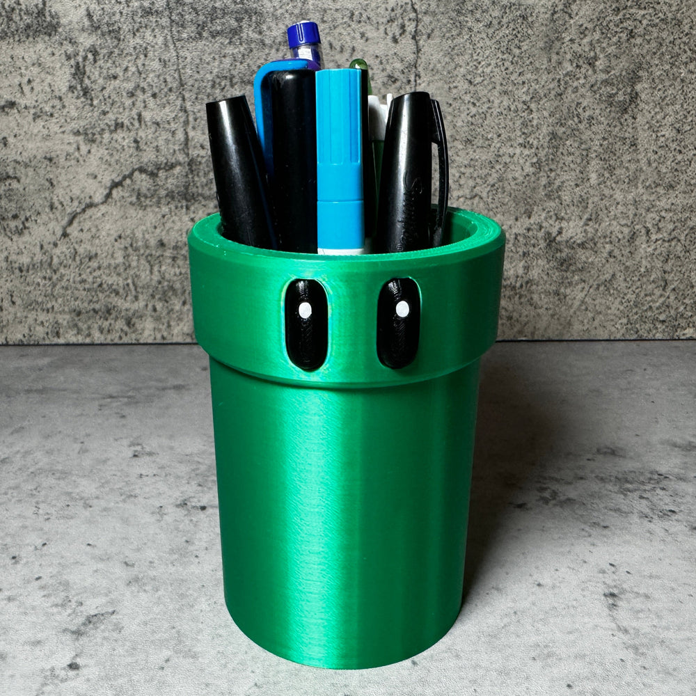 a green cup with pens and pens in it