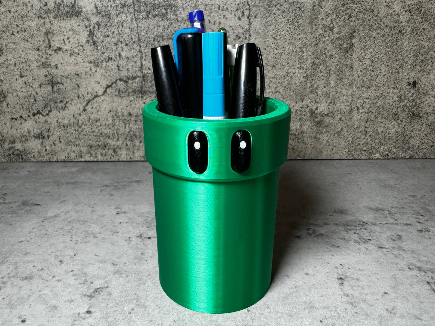 a green cup with pens and pens in it