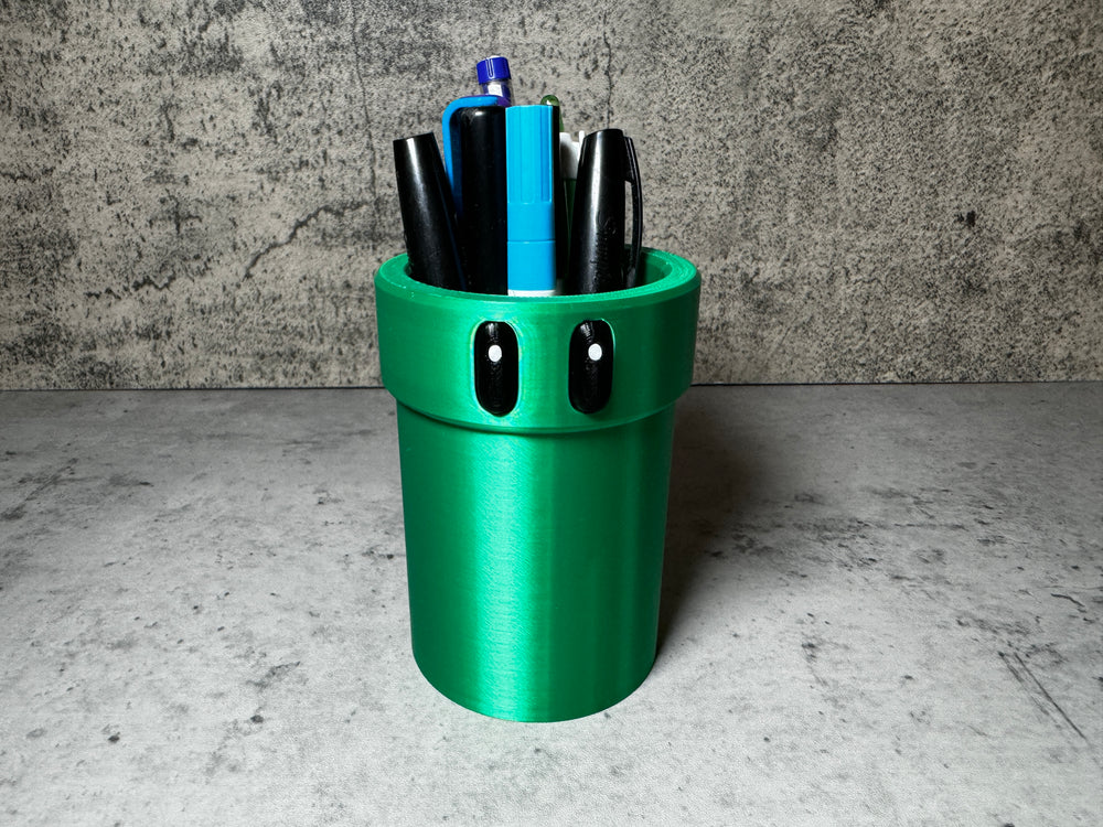 a green cup with pens and pens in it
