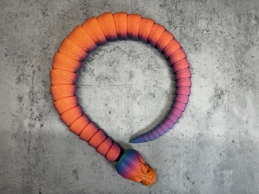 
                  
                    an orange and purple snake toy on a concrete surface
                  
                