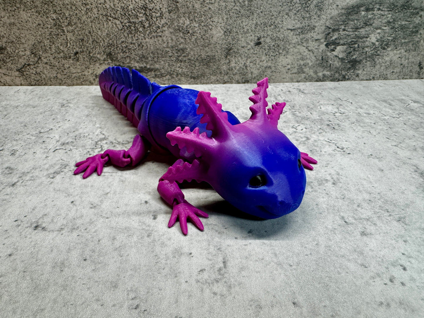 a blue and purple toy lizard laying on the ground